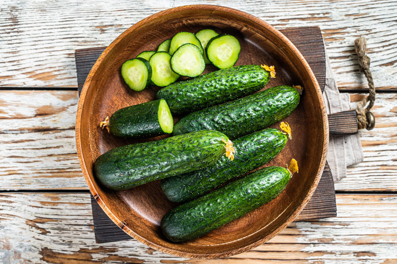 Raw organic Cucumbers in a wooden plate. White Wooden background Cucumber Diet